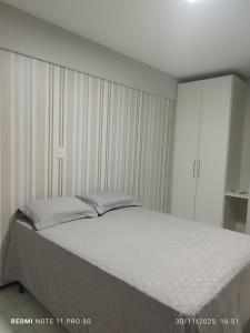 una camera da letto con un letto grande con lenzuola bianche di Flat Biarritz - Praia Litorânea a São Luís