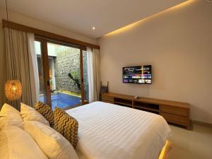 a bedroom with a large white bed and a window at Genta Villa Bali in Sanur