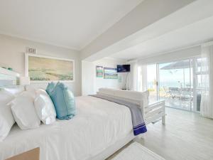 a white bedroom with a bed and a view of the ocean at Harker Street Sea Facing Studio in Plettenberg Bay +36 photos
