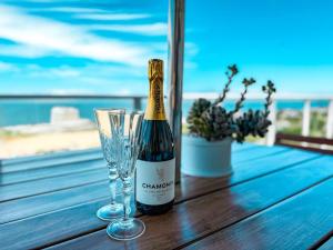 a bottle of champagne and two glasses on a wooden table at Harker Street Sea Facing Studio in Plettenberg Bay
