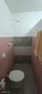 a bathroom with a white toilet in a red wall at Pousada Vôo Livre in Serra Talhada