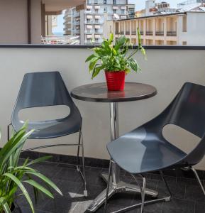 zwei Stühle und ein Tisch mit einer Topfpflanze auf einem Balkon in der Unterkunft Acapulco Hotel in Cattolica