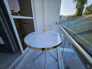 ein Glastisch auf einem Balkon mit einem Getränk darauf in der Unterkunft Charming cosy apartment in Mtwapa