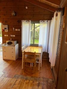 einen Holztisch und Stühle in einem Zimmer mit Fenster in der Unterkunft בקתת היערן- בטבע פראי למשפחות ולזוגות in Merom Golan + 7 Fotos