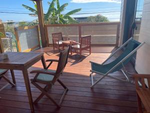 a deck with chairs and a table and a table and chairs at Bungalow grand T2 saint leu in Saint-Leu +5 photos