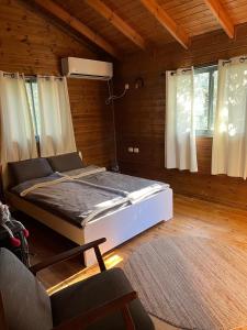 ein Schlafzimmer mit einem Bett in einem Zimmer mit Fenstern in der Unterkunft בקתת היערן- בטבע פראי למשפחות ולזוגות in Merom Golan
