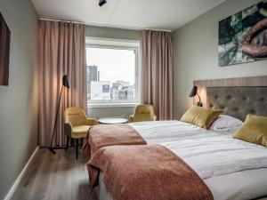 a bedroom with a large bed and a window at Quality Hotel Grand Tromsø in Tromsø