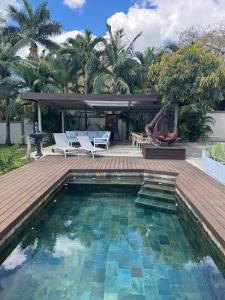 a swimming pool with chairs and a wooden deck at Lakaz Mapou - Magnifiques Appartements rénovés de 3 chambres et 2 salles de bains in Rivière Noire