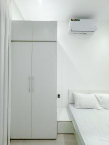 1 dormitorio blanco con 1 cama y armario blanco en Cozy Boutique Chilling, en Buon Ma Thuot