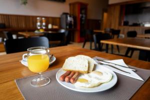 a plate of eggs and sausage and a glass of orange juice at GUMBELA - Hotel in São Tomé