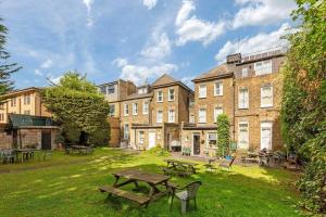 Amhurst Hotel في لندن: حديقة بها مقاعد وطاولات أمام المبنى