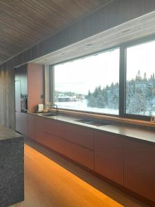 Una cocina con una gran ventana y un fregadero grande. en Architect Designed Mountain Cabin At Kvitfjell, en Favang