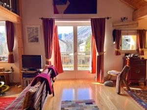 Una sala de estar con una gran ventana y un televisor. en Chesa Principela - La Punt, en La Punt-Chamues-ch