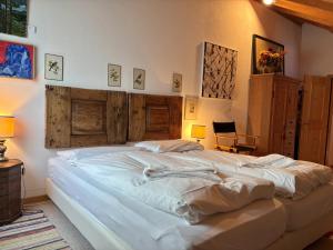 1 cama blanca grande en un dormitorio con paredes de madera en Chesa Principela - La Punt, en La Punt-Chamues-ch