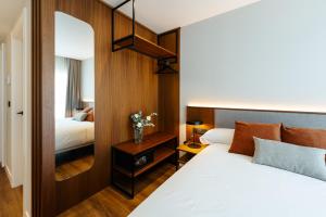 a hotel room with a bed and a mirror at Apartamentos 2H LIVING in León