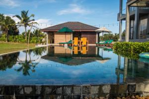 a swimming pool in front of a house with a resort at Six Elements Beach Villa in Tangalle