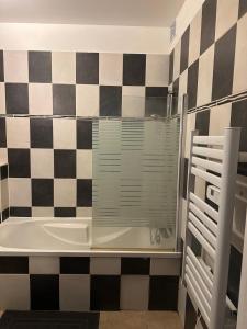 bagno con vasca e parete a scacchi di AGREABLE T3 1er étage a La Celle-sous-Gouzon