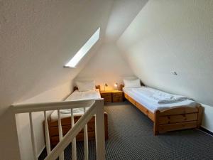 a attic room with two beds and a staircase at Adlerhorst - Moderne 60 qm Wohnung mit Terrasse in Oevenum