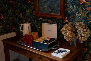 a table with a box of lipstick and flowers on it at Le Petit Serrant - maison d'hôtes d'exception in Bouchemaine