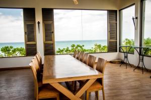 a dining room with a table and chairs and the ocean at Six Elements Beach Villa in Tangalle