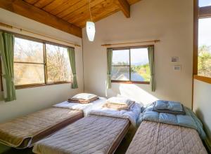 two beds in a room with two windows at Beautiful Nasu, the center of Nasu, Up to 12 people, 3 bedrooms, BBQ on the deck, night karaoke in Nasu