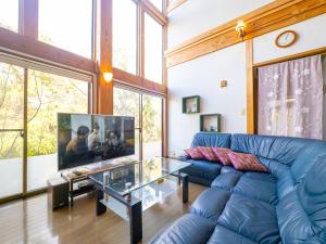 a living room with a blue couch and a glass table at Beautiful Nasu, the center of Nasu, Up to 12 people, 3 bedrooms, BBQ on the deck, night karaoke in Nasu