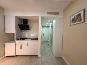 巴统Alliance palace Black Sea的厨房配有白色橱柜、水槽和走廊 更多27张照片