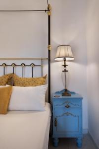 Valletta Townhouse Suite with a Maltese Balcony في إيل فورجانا: سرير مع طاولة بجانب السرير زرقاء اللون ومصباح عليها