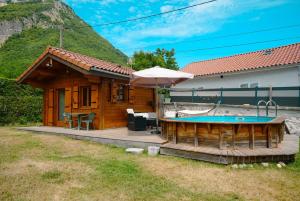 a small wooden house with a pool and an umbrella at Petit chalet avec piscine privée in Lumbin