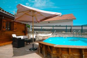 a patio with an umbrella and a swimming pool at Petit chalet avec piscine privée in Lumbin