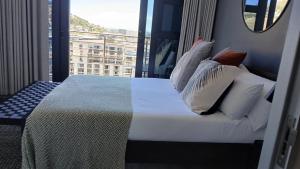 una camera da letto con un letto con cuscini e una finestra di City Slick Hideaway a Città del Capo Altre 14 foto