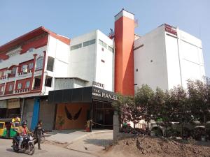 Dos personas en motocicleta frente a un edificio. en Hotel The Grand Ranjeet, en Indore