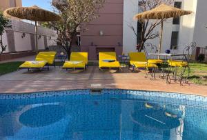 una piscina con sillas y mesas amarillas y sombrillas en philippe ayache, en Marrakech