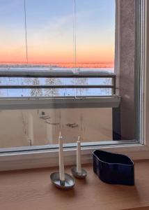 deux bougies assises sur une table devant une fenêtre dans l'établissement Penthouse Ounas with Private Sauna, à Rovaniemi 29 autres photos