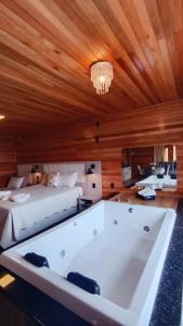 a large bath tub in a bedroom with a bed at Cabana Alpen Ville 01 - Rural com Banheira de Hidromassagem in Bom Jardim da Serra