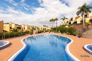 - une piscine dans un complexe avec des palmiers et des bâtiments dans l'établissement Villa Meloneras III, à Maspalomas