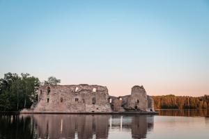 an old castle sitting in the middle of a lake at Ragnar Glamp Koknese Forest in Koknese