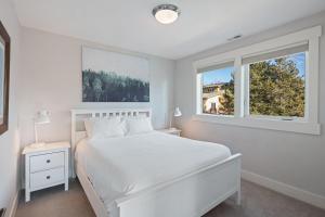 a white bedroom with a white bed and two windows at Hillside Haven in Bend