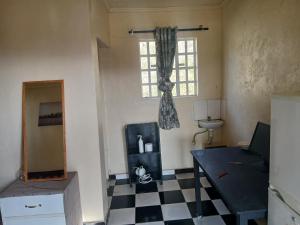a living room with a checkered floor and a window at Lions Gate Kisamis Guest House in Kiserian