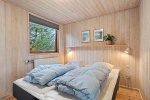 una camera da letto con un letto con cuscini blu e una finestra di BL1144-Blokhus-Sixtusvej-27 a Hune