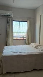ein Schlafzimmer mit einem Bett und einem Fenster mit Aussicht in der Unterkunft Salinópolis Praia in Salinópolis