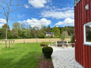 a red building with a bench and a grass field at Ferien am Winkelhof in Deggenhausertal