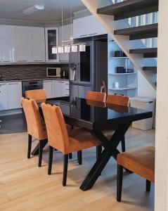 120n Villa Hietala paritalo, 1-8henkilön LUXUS majoitus, 3x160cm jenkkisängyt Löhösohvat, iso takaterassi, täyd keittiö Kodink, laatu sauna, Takka, Tv 75" x2, 2wc, autokatos, avainboxi koodilla, itsekirjaus 24h, wifi ja 500mb kuitunetti, kuivaava pesukone في سينايوكي: مطبخ مع طاولة سوداء مع كراسي وسلالم