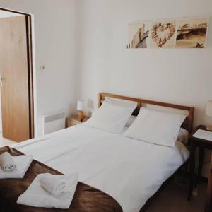 Un dormitorio con una cama blanca con cabecero de madera. en Acacias Hôtel Motel, en Vendays-Montalivet