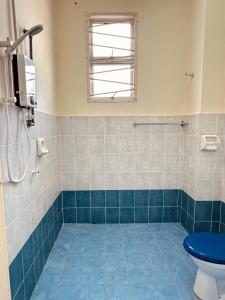 bagno con servizi igienici blu e finestra di Rumah Eve Taman Banting Baru Mvslim Only a Banting
