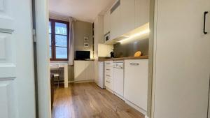 uma cozinha com armários brancos, uma mesa e uma janela em El Refugio de Enveitg em Enveitg