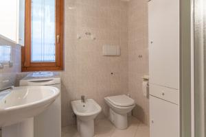 a white bathroom with a sink and a toilet at Trilo La Rindela in Folgaria
