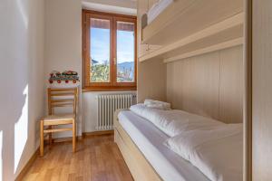 a bedroom with a bed and a chair and a window at Trilo La Rindela in Folgaria