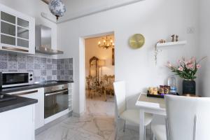 Valletta Townhouse Suite with a Maltese Balcony في إيل فورجانا: مطبخ مع خزائن بيضاء وطاولة وكراسي +21 صورة