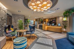 a woman sitting in a chair in a lobby at Point A Hotel London Shoreditch in London